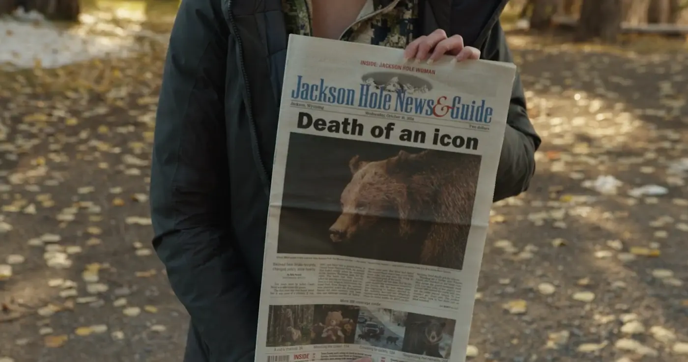 A person holding a Jackson Hole News and Guide with the headline Death of an icon